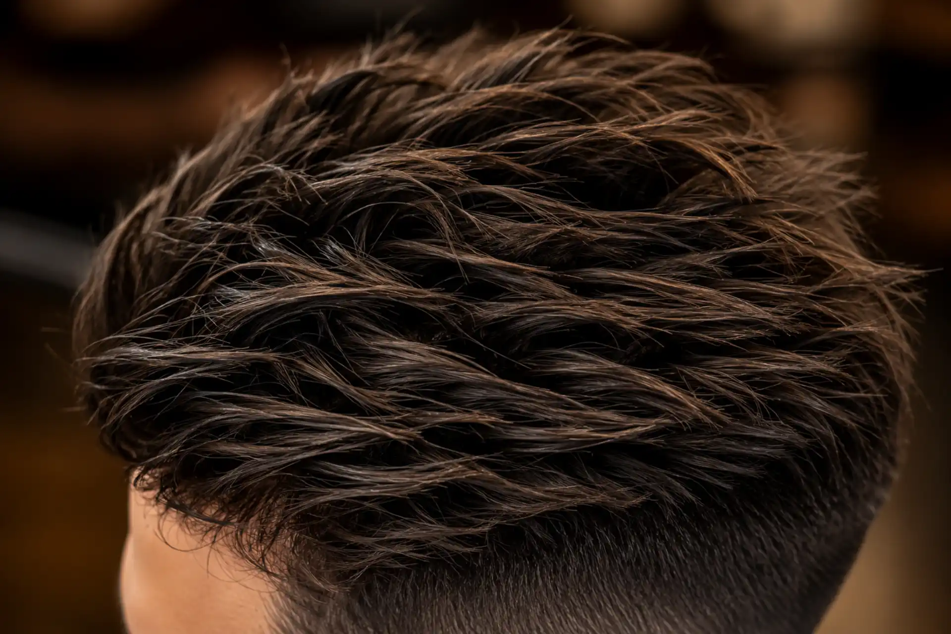 Gros plan sur le dessus d'une undercut texturée avec volume et mèches travaillées, réalisée au Salon Mickael Roman