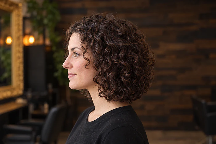Coupe pour cheveux bouclés : boucles définies et forme arrondie, de profil