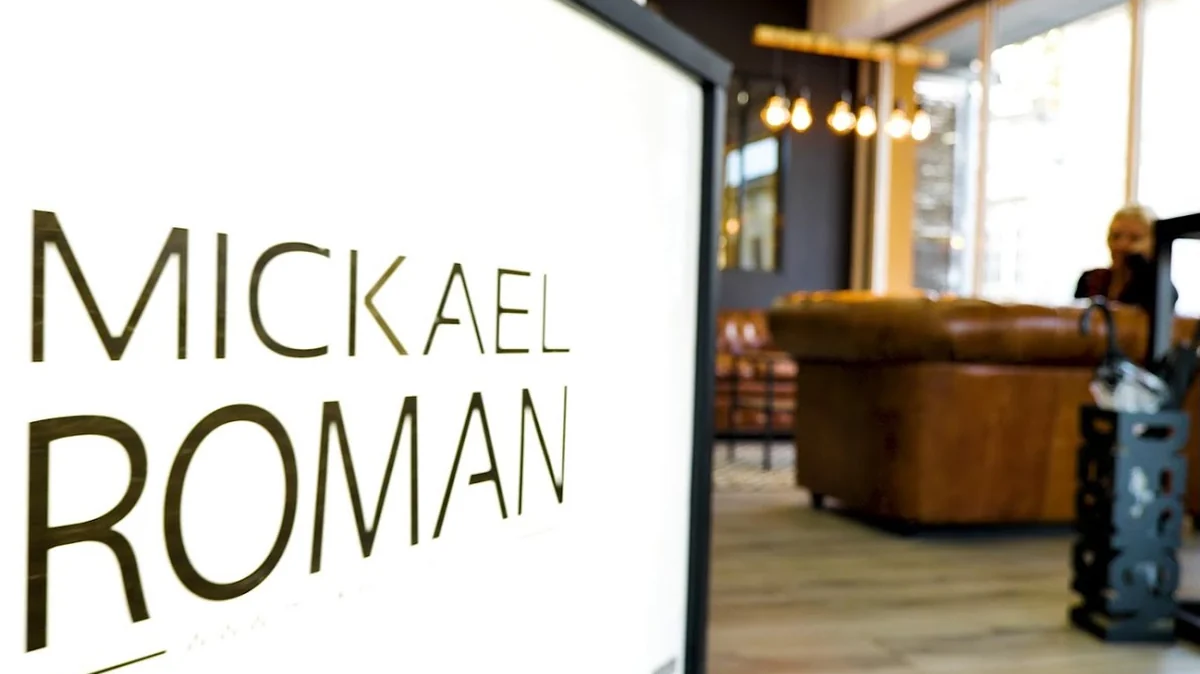 Entrée du Salon Mickael Roman à Vayres : logo sur la vitre, canapé en cuir et suspensions